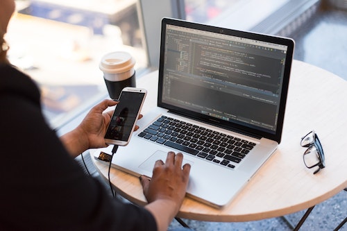 Man working on laptop with phone in hand DevOps.