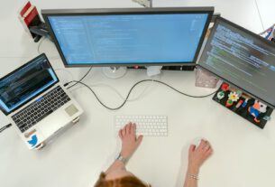 Person working on three computer screens.