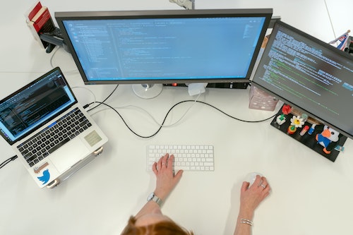 Person working on three computer screens.